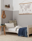 Nursery room with the Alba cot bed in toddler bed mode, a world map poster, and a small table.