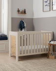Alba mini cot bed in a modern nursery with a grey wall and a window.