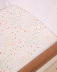 Close-up of the Good Life bedside crib fitted sheet in soft cream with playful vegetable and garden motifs