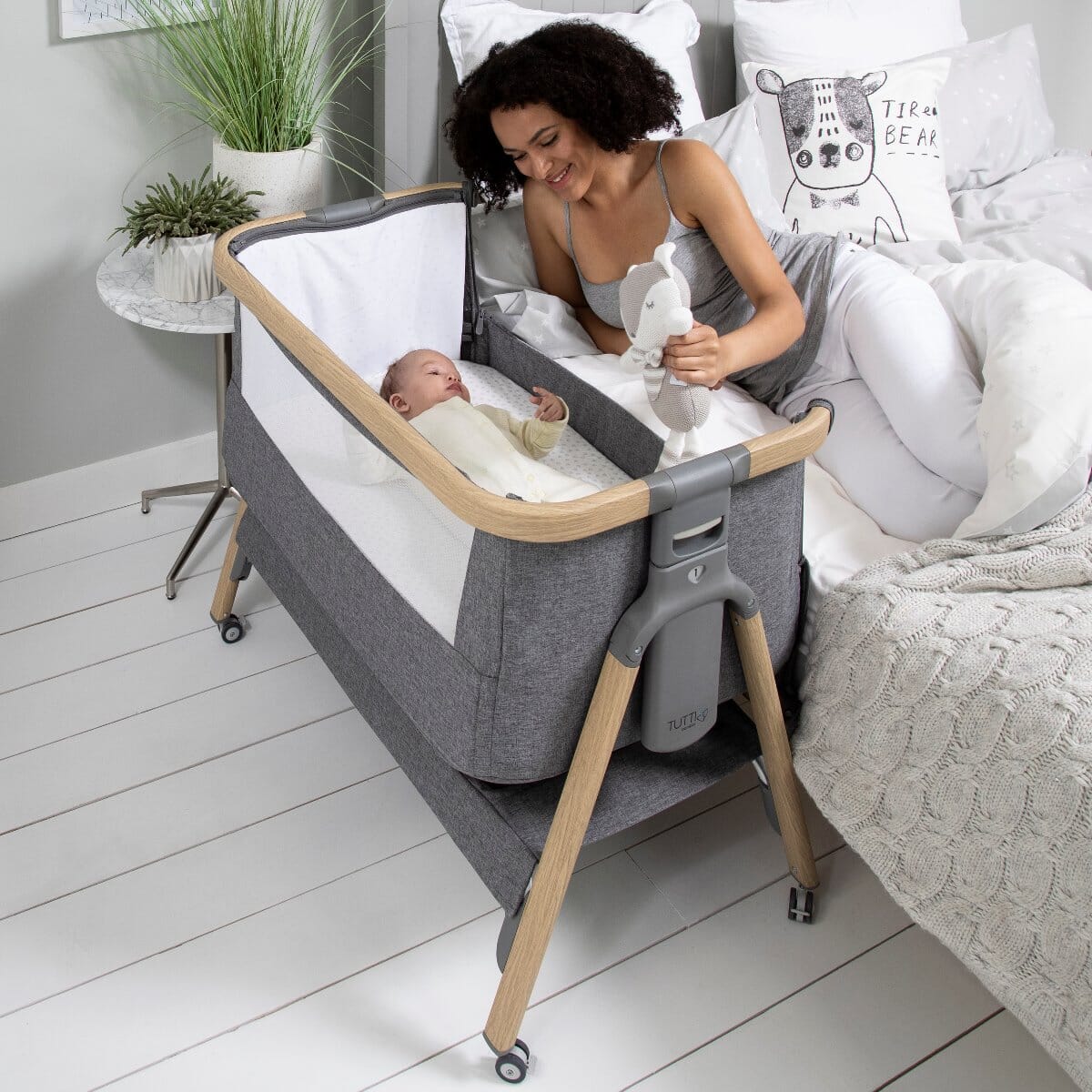 CoZee Air Bedside Crib in Oak and Charcoal- mother lying next to baby for easy co-sleeping functionality