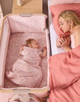 Overhead view of baby resting in the CoZee Air 2 bedside crib in blush, positioned securely alongside the parent’s bed.