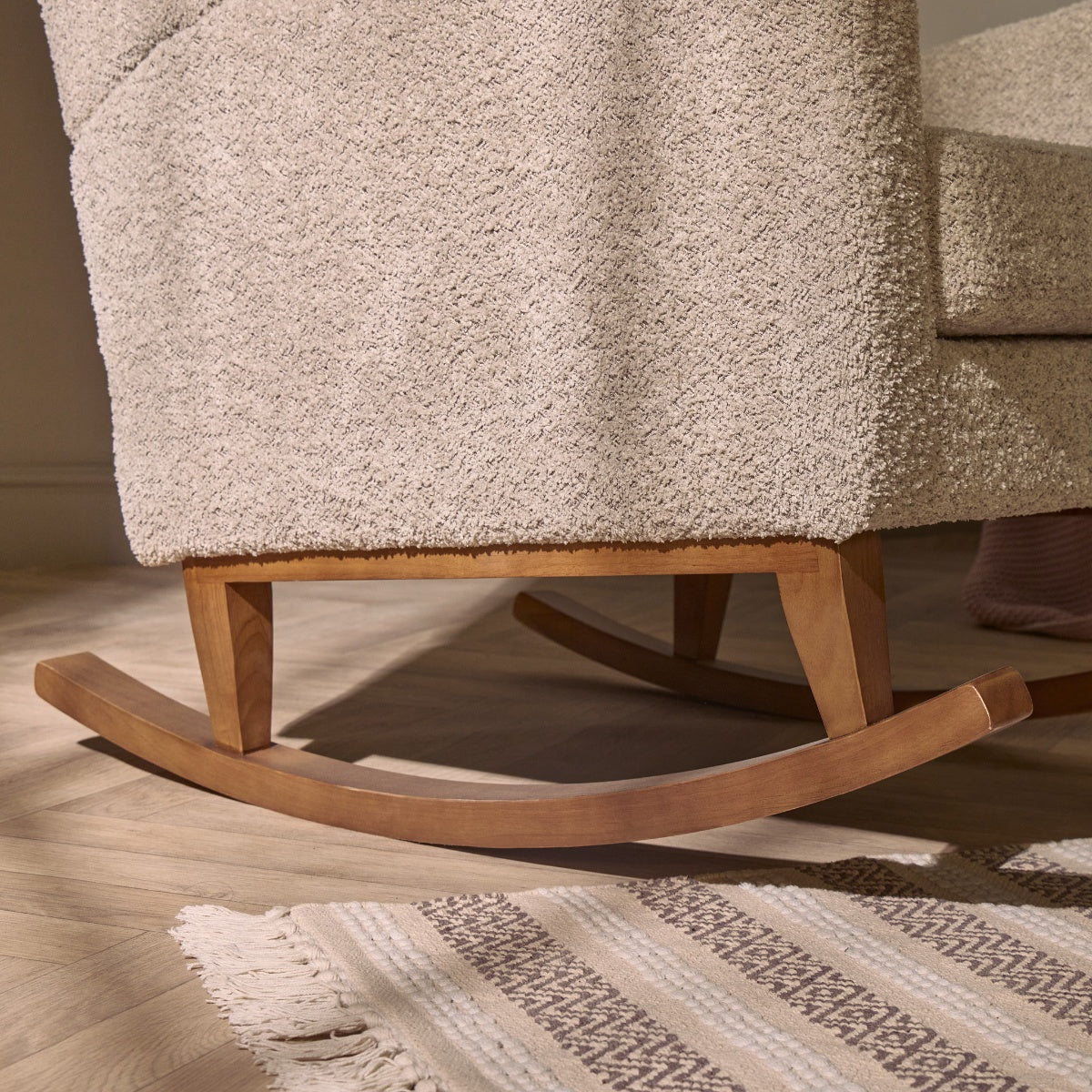 Close-up of the Harper Wingback rocking chairโs wooden base in teddy mushroom, showcasing smooth rocking motion and curved rails.