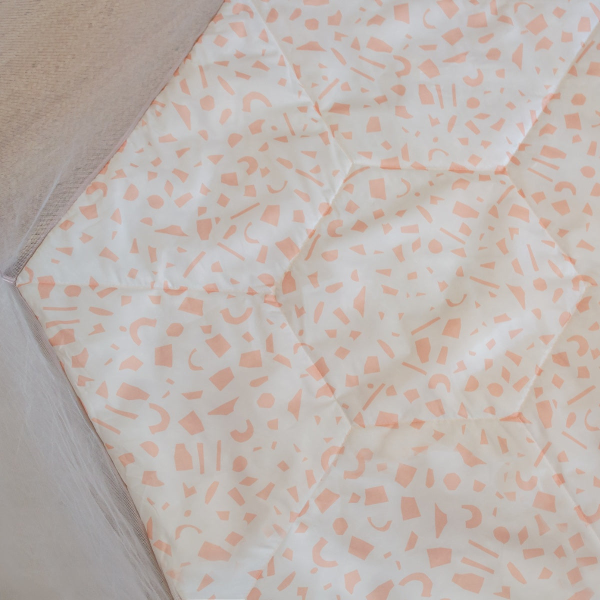 Overhead view of the Hexa Playpen in Gumdrop Terrazzo highlighting the padded play mat with soft pink terrazzo shapes on white