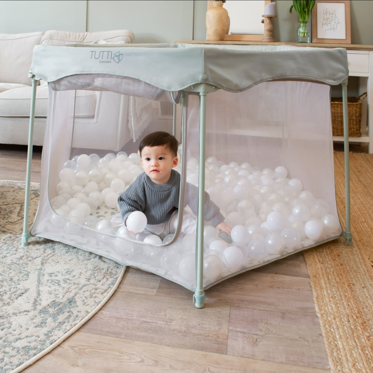 Child playing inside the Hexa playpen in Leaf Terrazzo, surrounded by white balls and protected by mesh sides for visibility and airflow