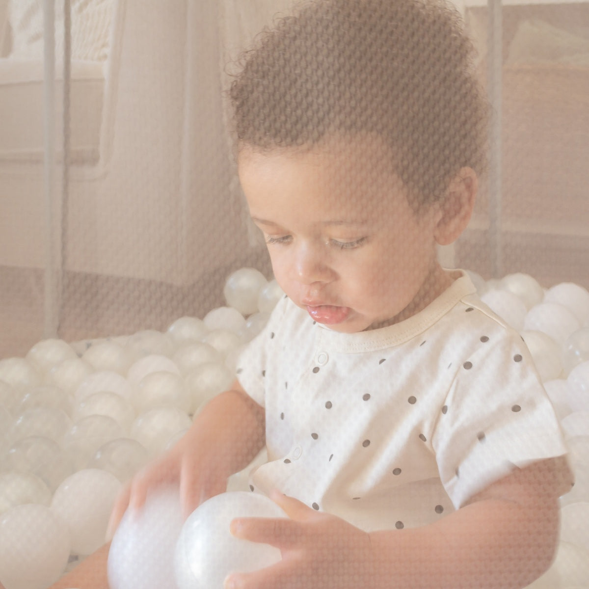 Close-up of baby inside the Ocean Stone Terrazzo Hexa playpen, with mesh sides gently diffusing light and soft textures