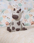 Plush cow toy on a patterned bedding in a bed