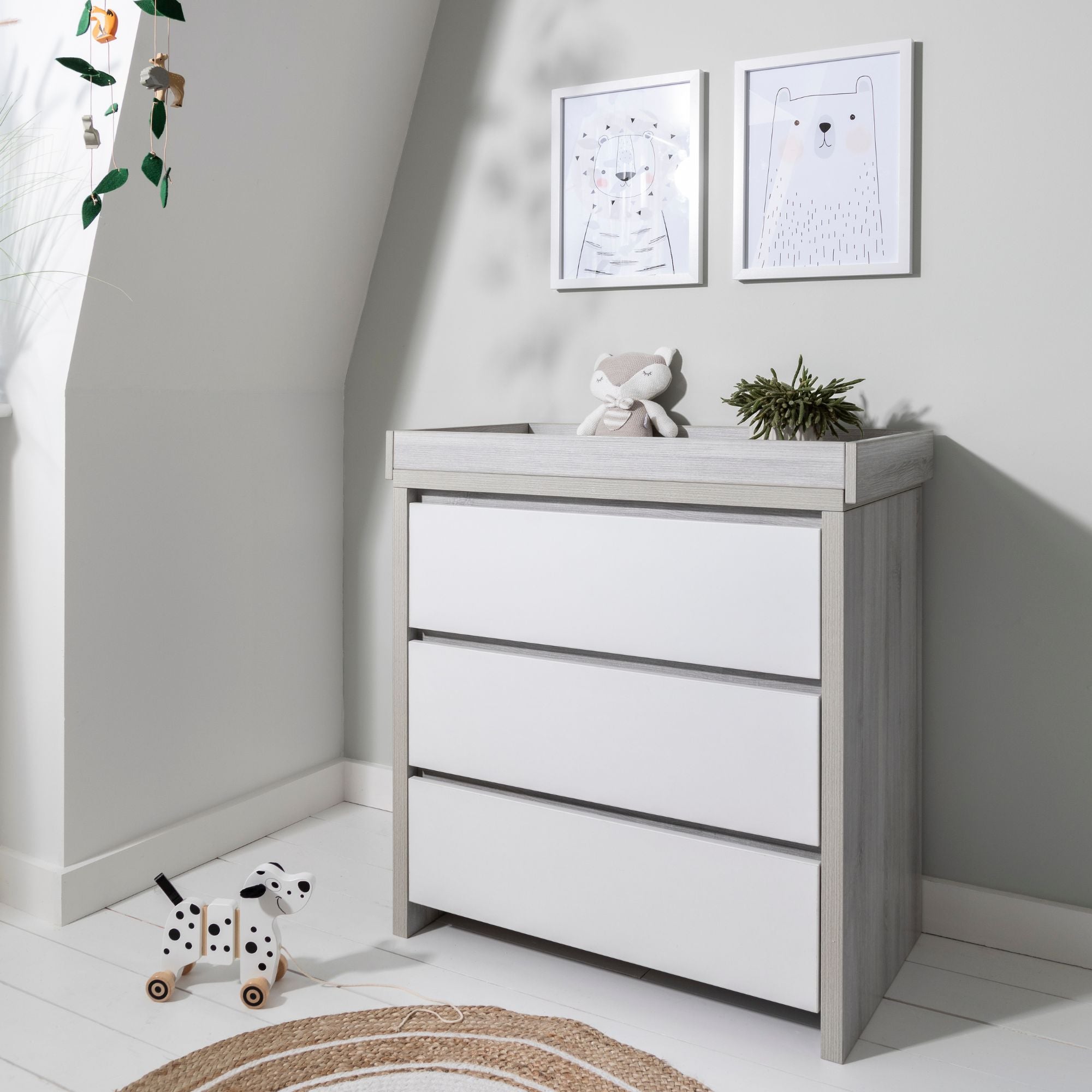 Modena Changing Unit in Grey Ash and White styled in a nursery setting, providing a functional space for changing and storing baby items.