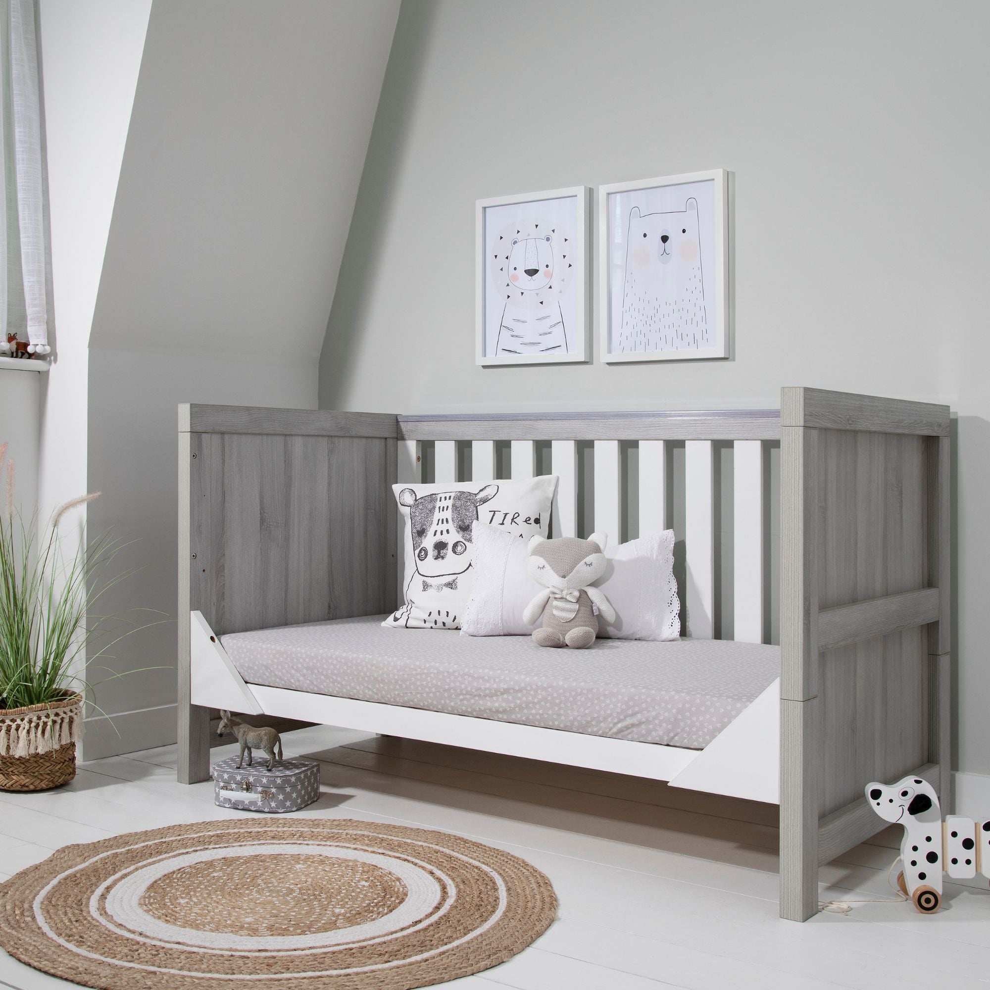 Modena Cot Bed in Grey Ash and White converted into a comfortable sofa bed, showcasing its space-saving functionality and modern design in a serene nursery setting.