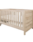 Modena Cot Bed in Oak with a contemporary slatted design and neutral wood finish, suitable for modern nursery interiors