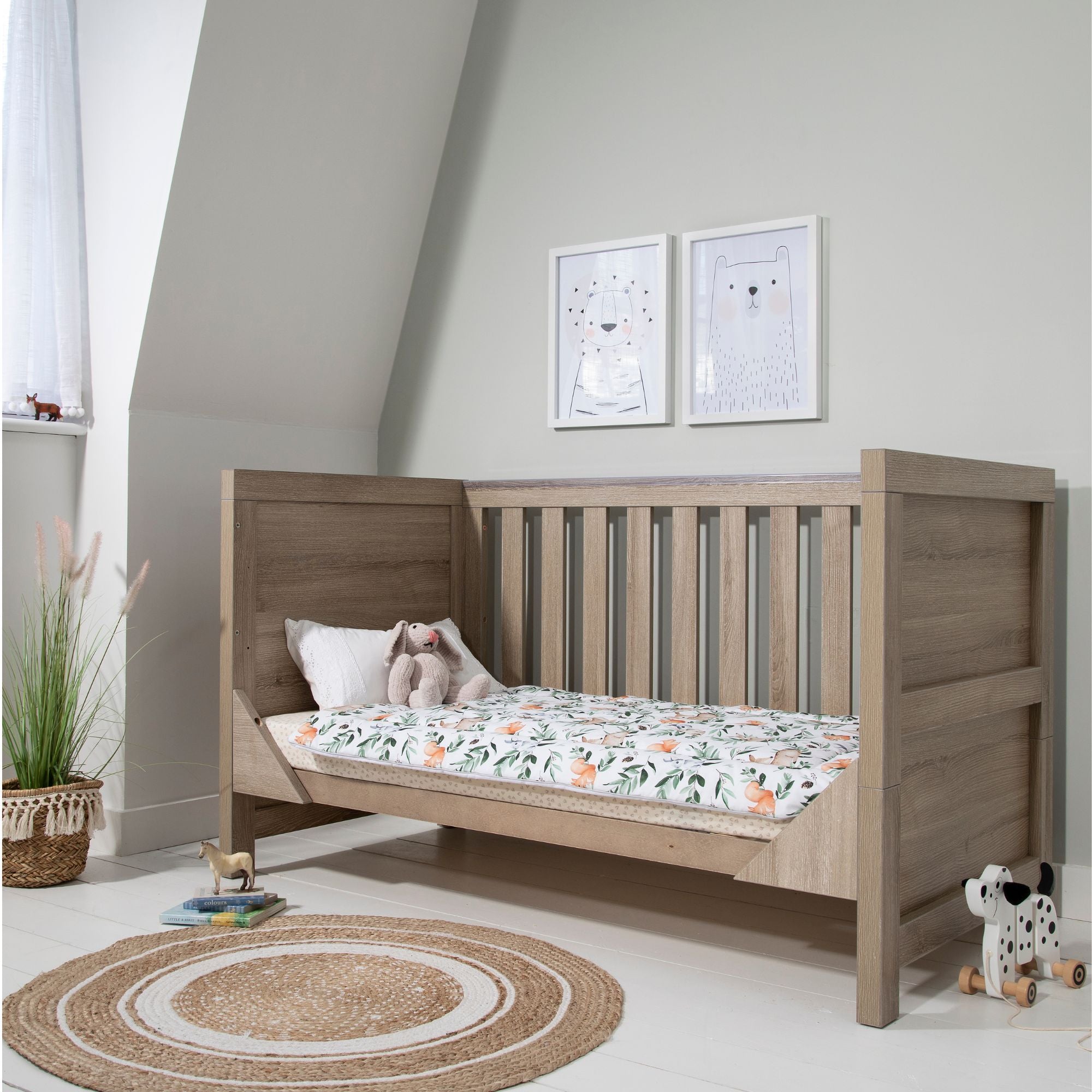 Modena Cot Bed in Oak shown in sofa bed mode, ideal for toddlers transitioning from cot to bed, providing a comfortable seating or lounging option.