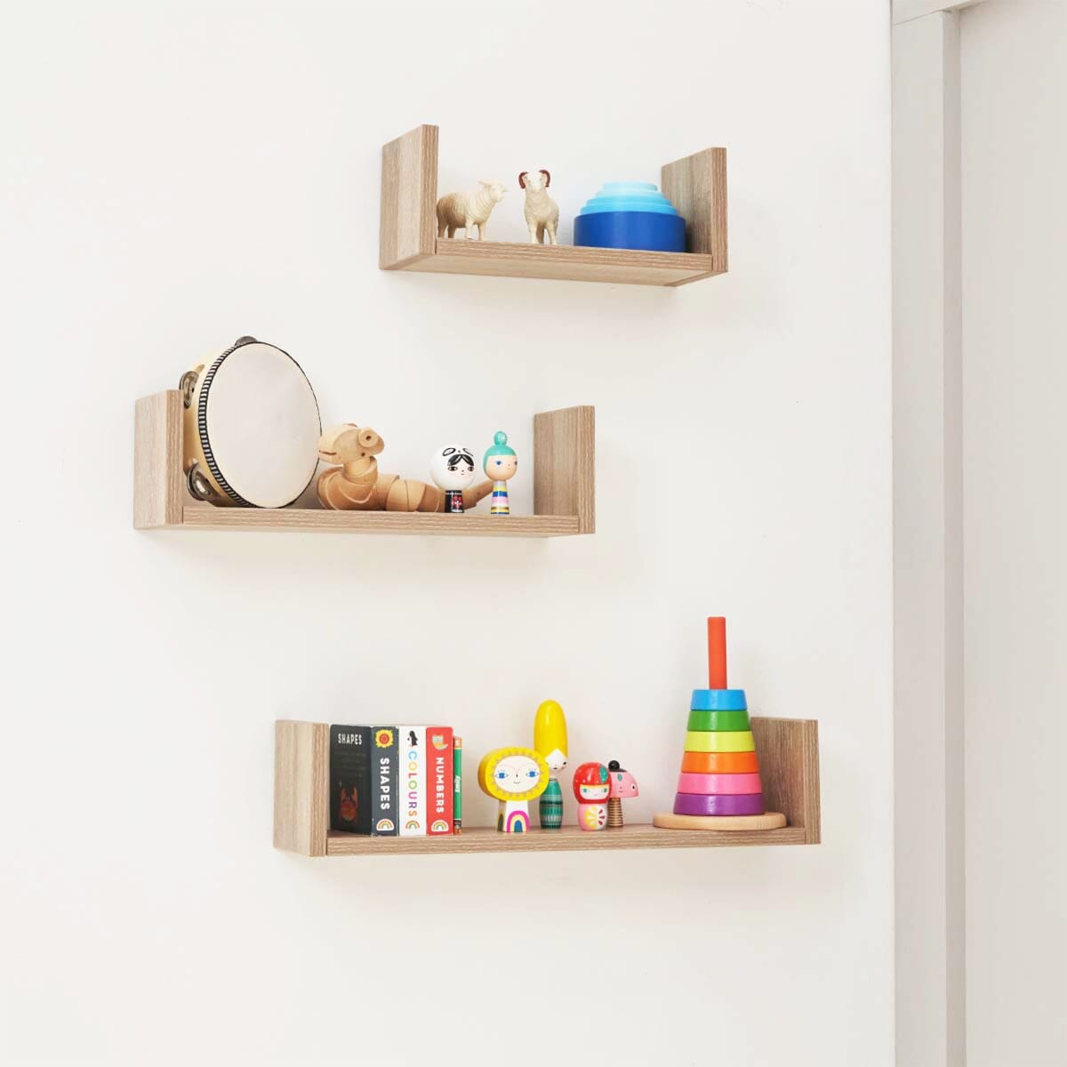 Modena Three U-Shaped Wall Shelves Oak installed the on wall, showcasing functional vertical storage for children's toys and colourful books