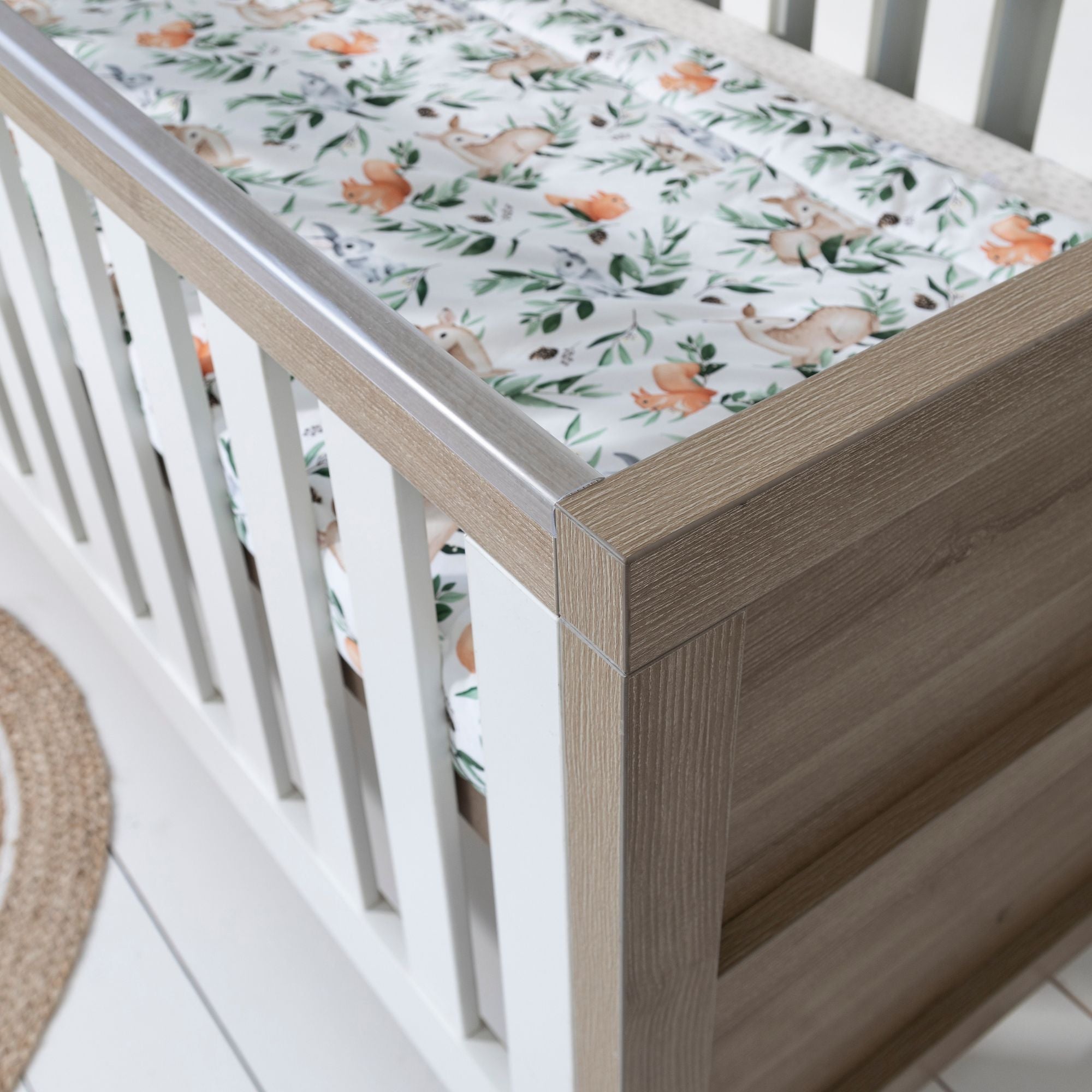 Close-up view of the Modena Cot Bed in White Oak and White highlighting protective teething rails and slatted sides, designed for both safety and durability in a modern nursery.