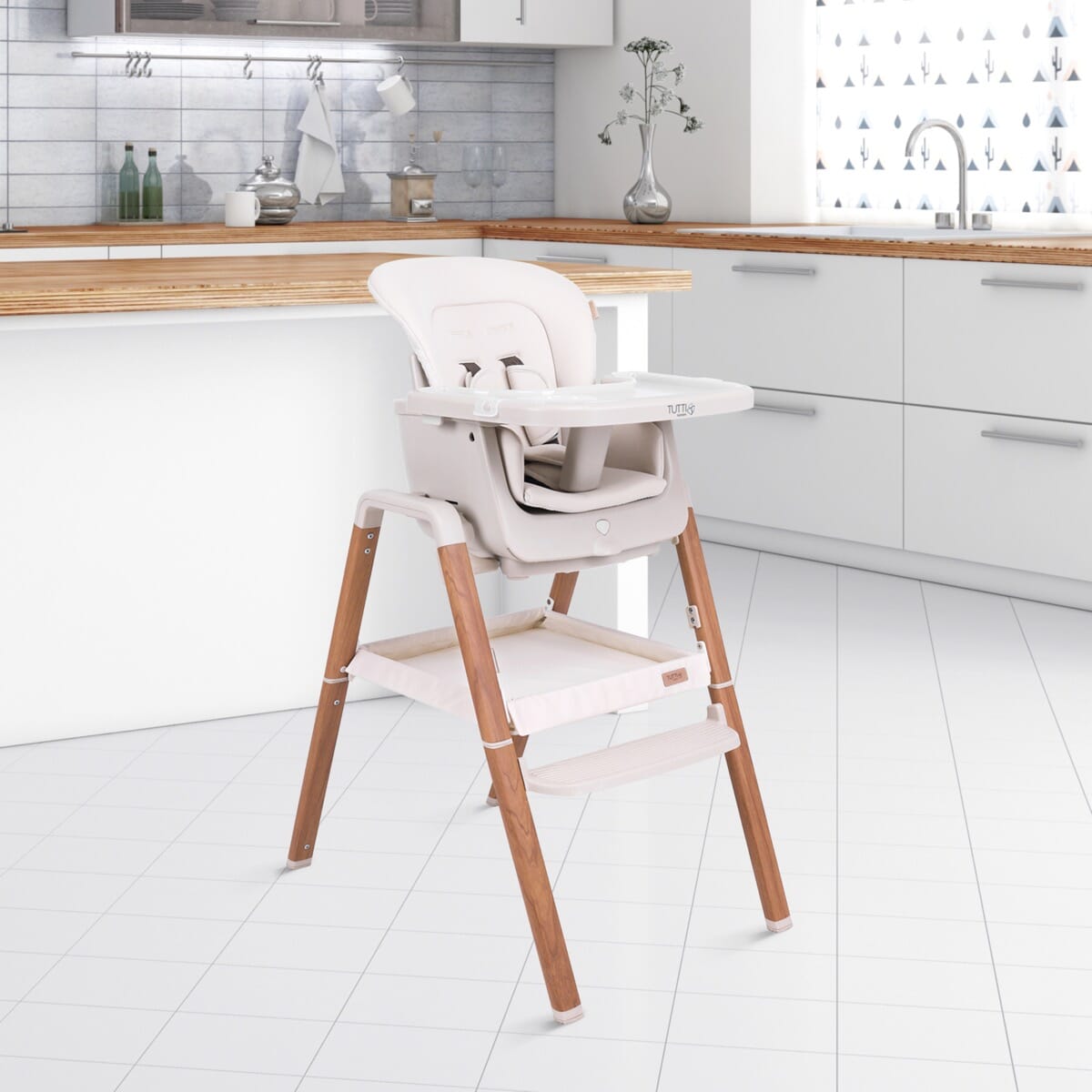 Lifestyle view of the Nova evolutionary highchair in Scandinavian Walnut/Ecru placed in a modern white kitchen, featuring adjustable tray, safety harness, and wipe-clean design.