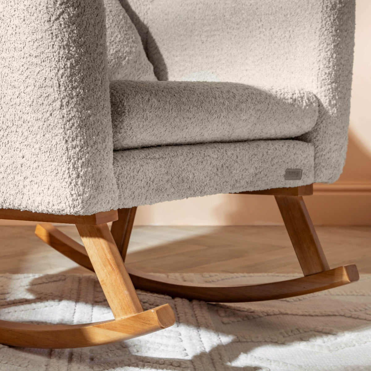 Close-up of the Oscar Luxe rocking chair and footstool in sage, highlighting the natural wood rocking base and boucle texture