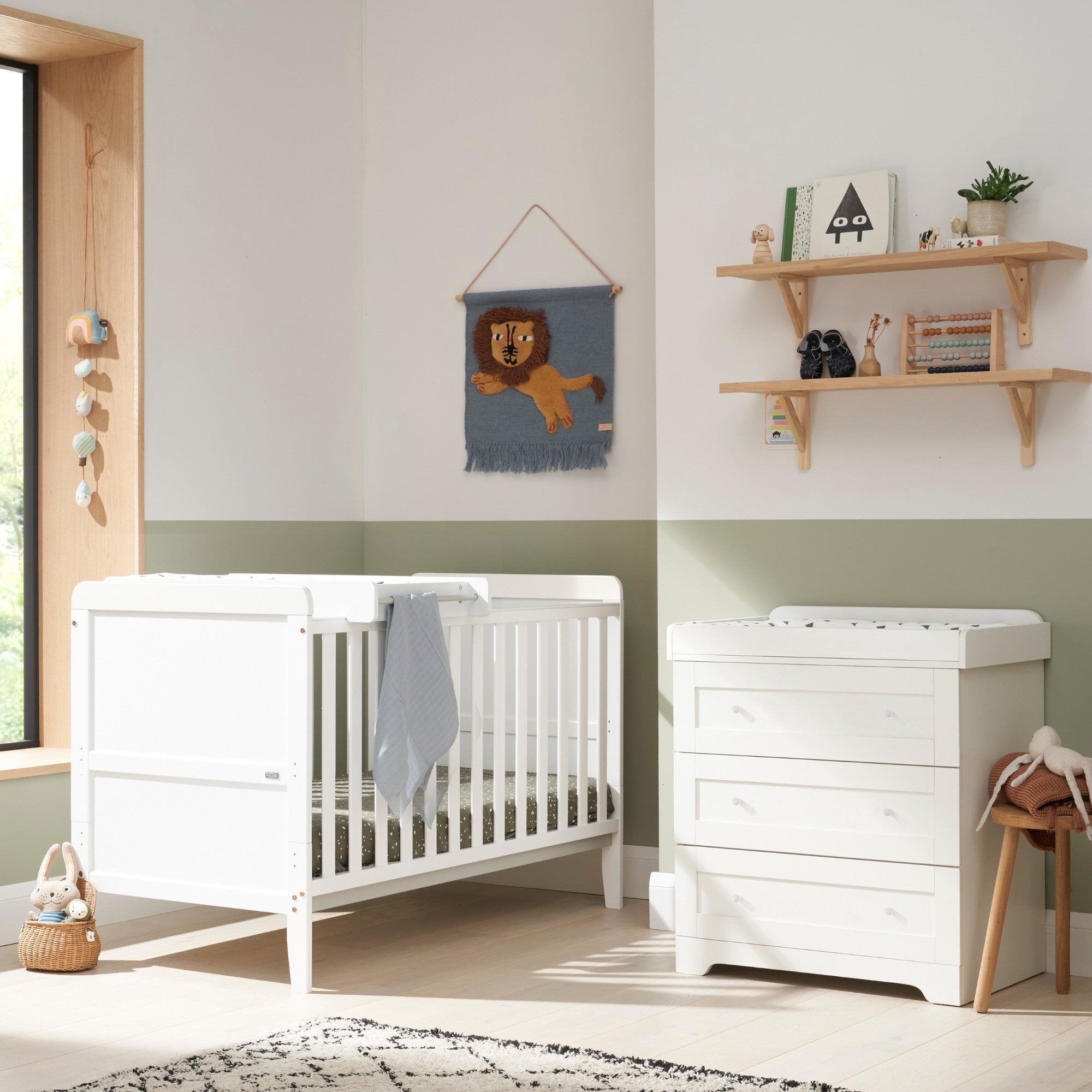 Room setting view of the Rio 2-piece nursery furniture set in White, featuring a cot bed with cot top changer and a chest changer with three spacious drawers for baby essentials.