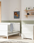 Room setting view of the Rio 2-piece nursery furniture set in White, featuring a cot bed with cot top changer and a chest changer with three spacious drawers for baby essentials.