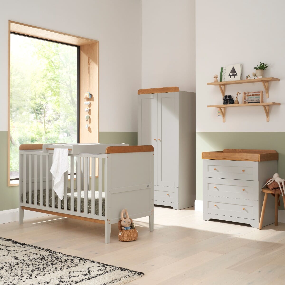 Nursery room view of the Rio three-piece room set in Honey Oak and Dove Grey, including a cot bed with top changer, a spacious wardrobe, and a chest changer for functional storage.
