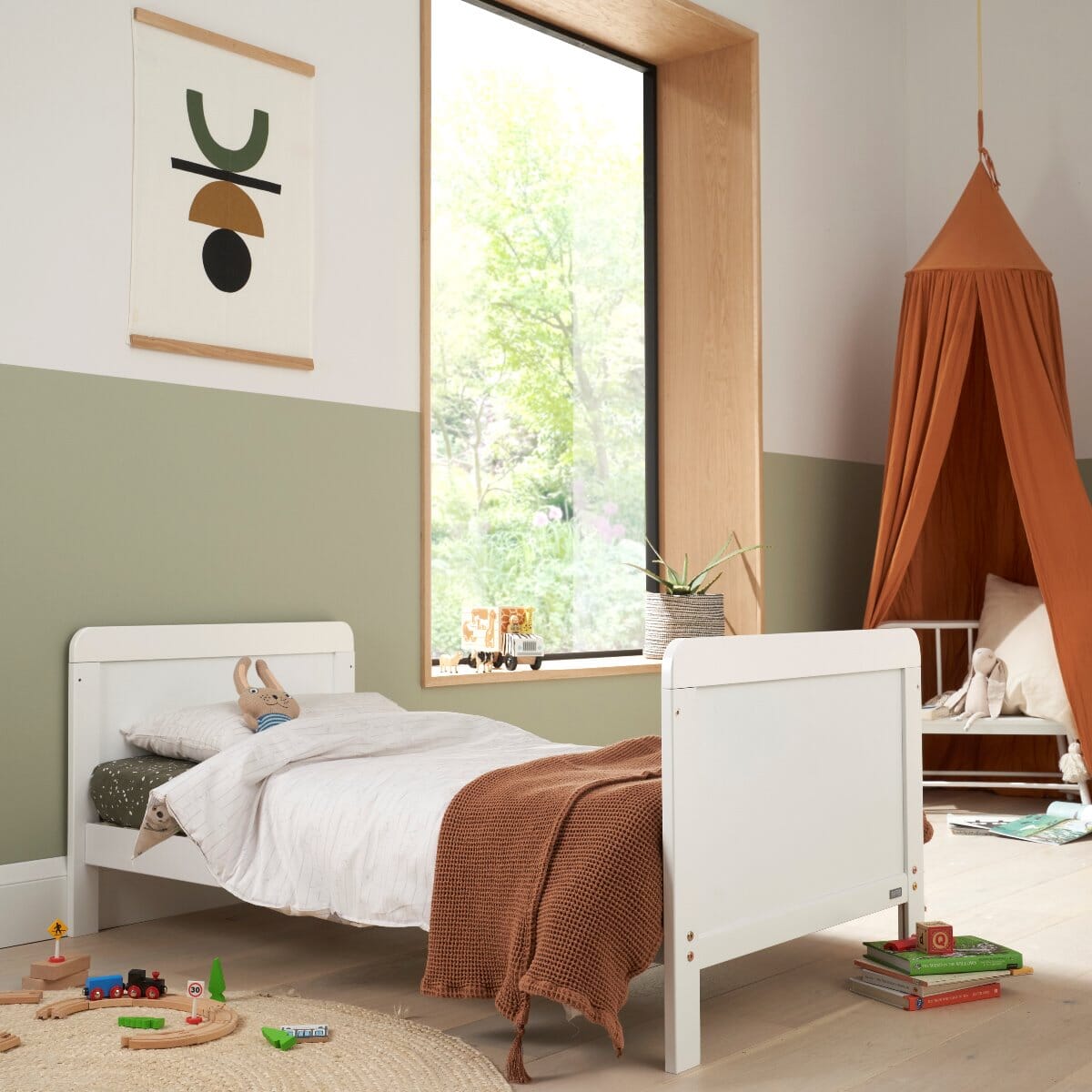 Rio Toddler Bed in white shown in a stylish nursery room, highlighting its solid panel design and low-to-ground frame for safe and easy toddler access.