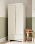 Lifestyle front view of Rio Wardrobe in White placed in a nursery setting, with dual doors and drawer for practical storage use.