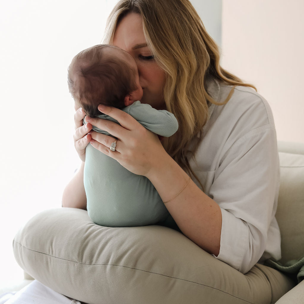 Mother kissing baby on birch SMO nursing pillow, highlighting soft organic fabric surface