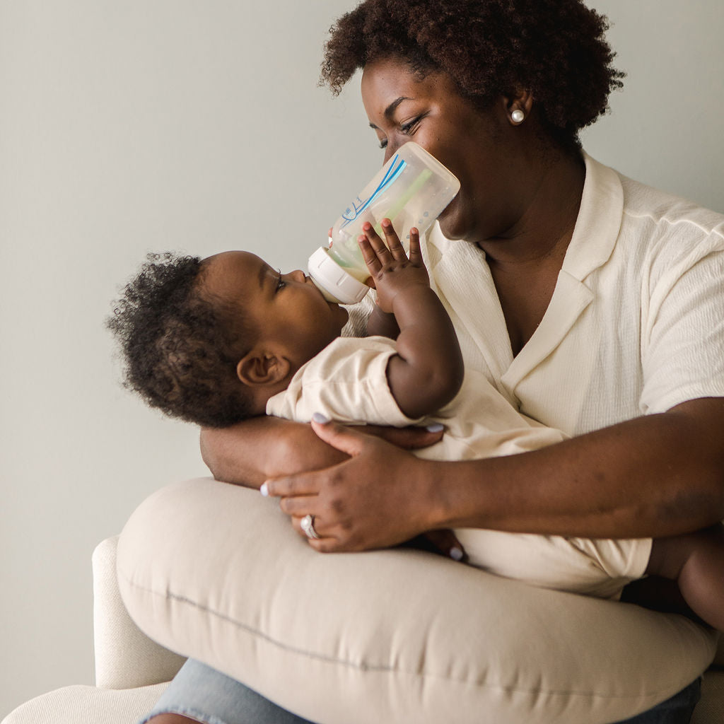 Mother bottle-feeding baby with SMO nursing pillow in birch, offering ergonomic support and comfort