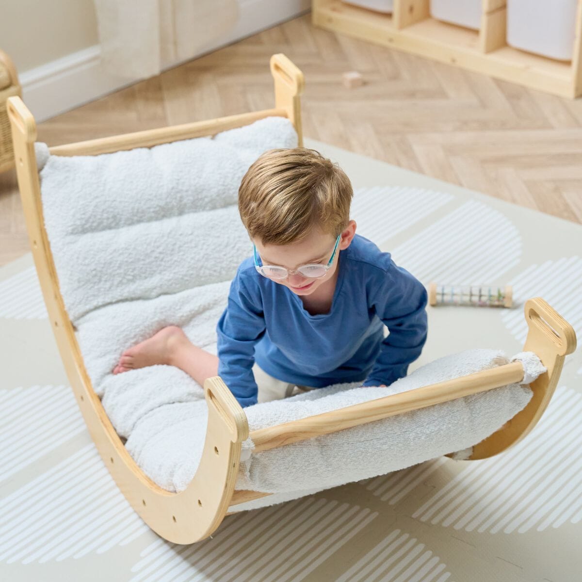 Young child climbing on the Scala Pikler with boucle natural cushion, showing supportive padding and safe, open-ended play
