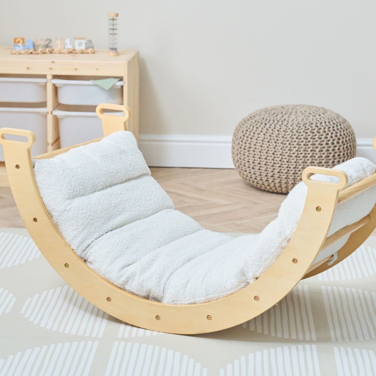 Scala Montessori Pikler rocking frame fitted with boucle natural cushion, styled in a modern playroom with wooden floor and neutral tones