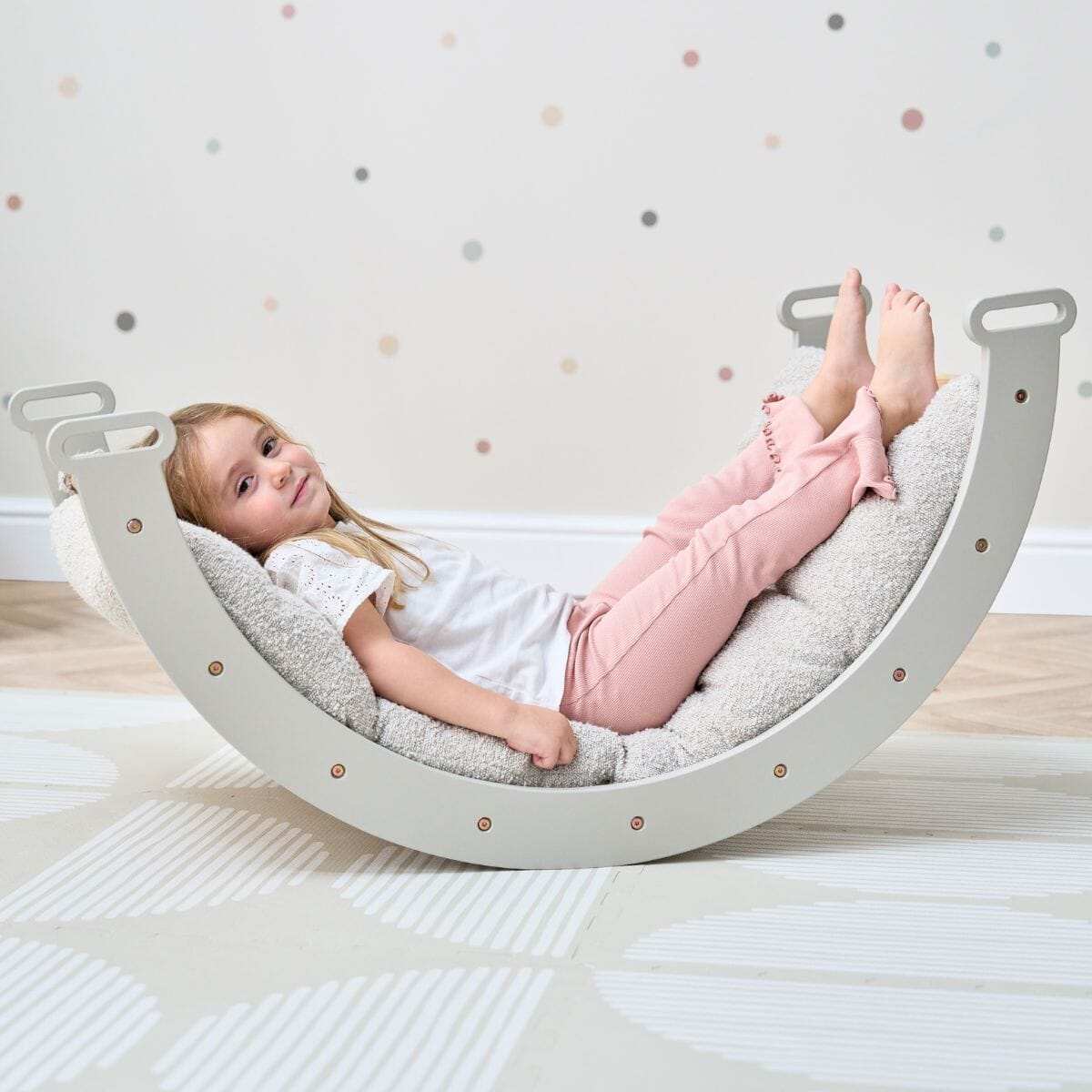 Girl relaxing on the Scala Montessori Pikler Cushion in Boucle Mushroom, highlighting soft texture and ergonomic support for comfort