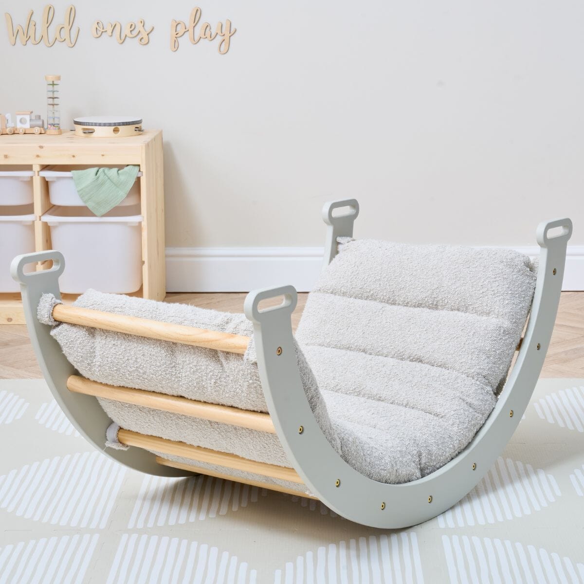 Nursery room view of Scala Montessori Pikler Cushion in Boucle Mushroom secured to rocking frame, styled with natural wood and soft tones