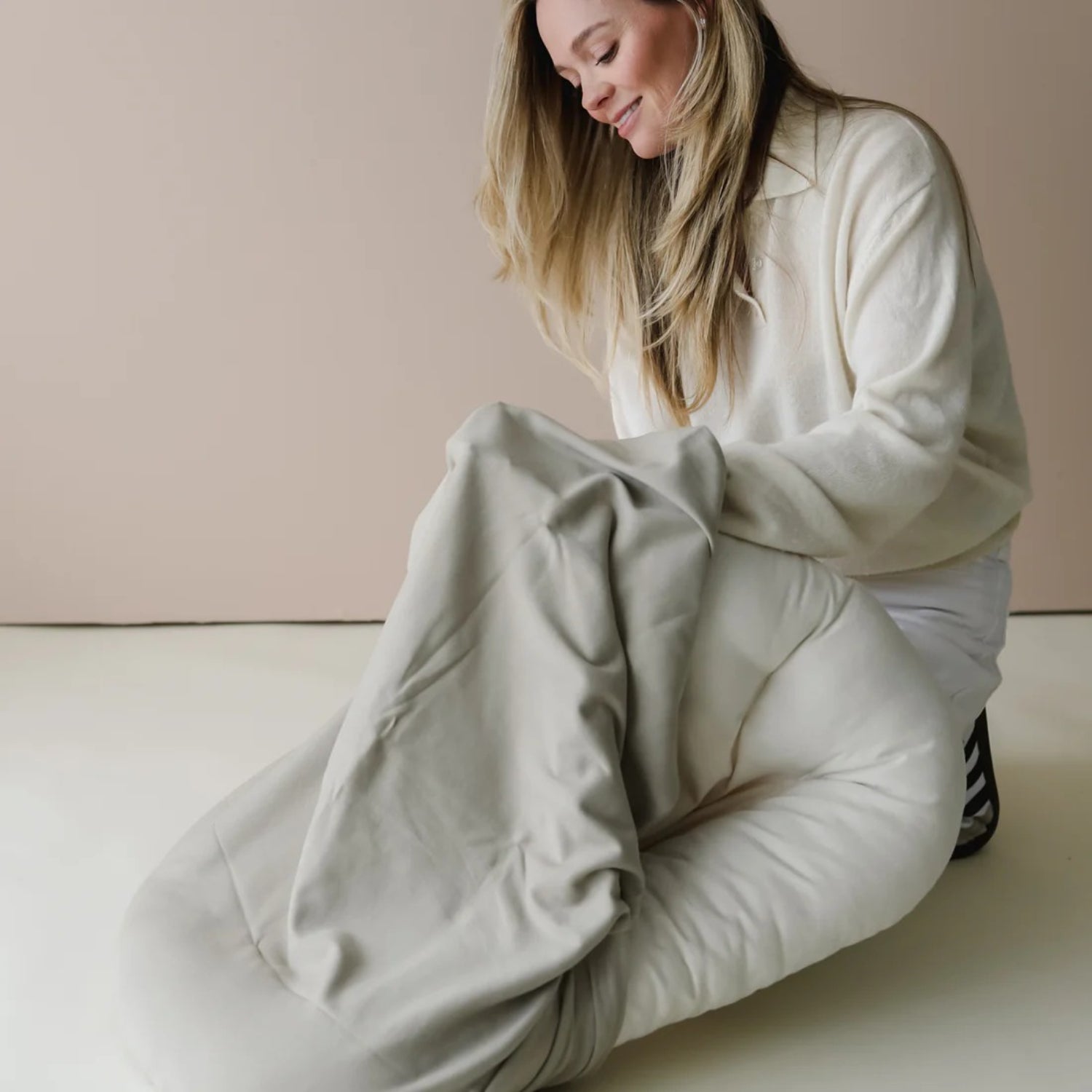 Parent adjusts the Snuggle Me lounger cover in birch, showing soft texture and snug fit over the baby lounger cushion