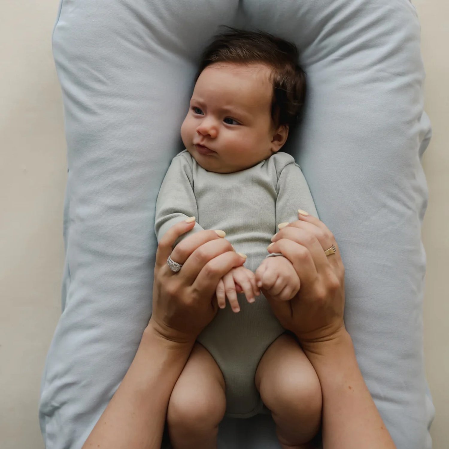Baby resting in Snuggle Me lounger with Bluebell cover – top-down view capturing gentle support and secure positioning