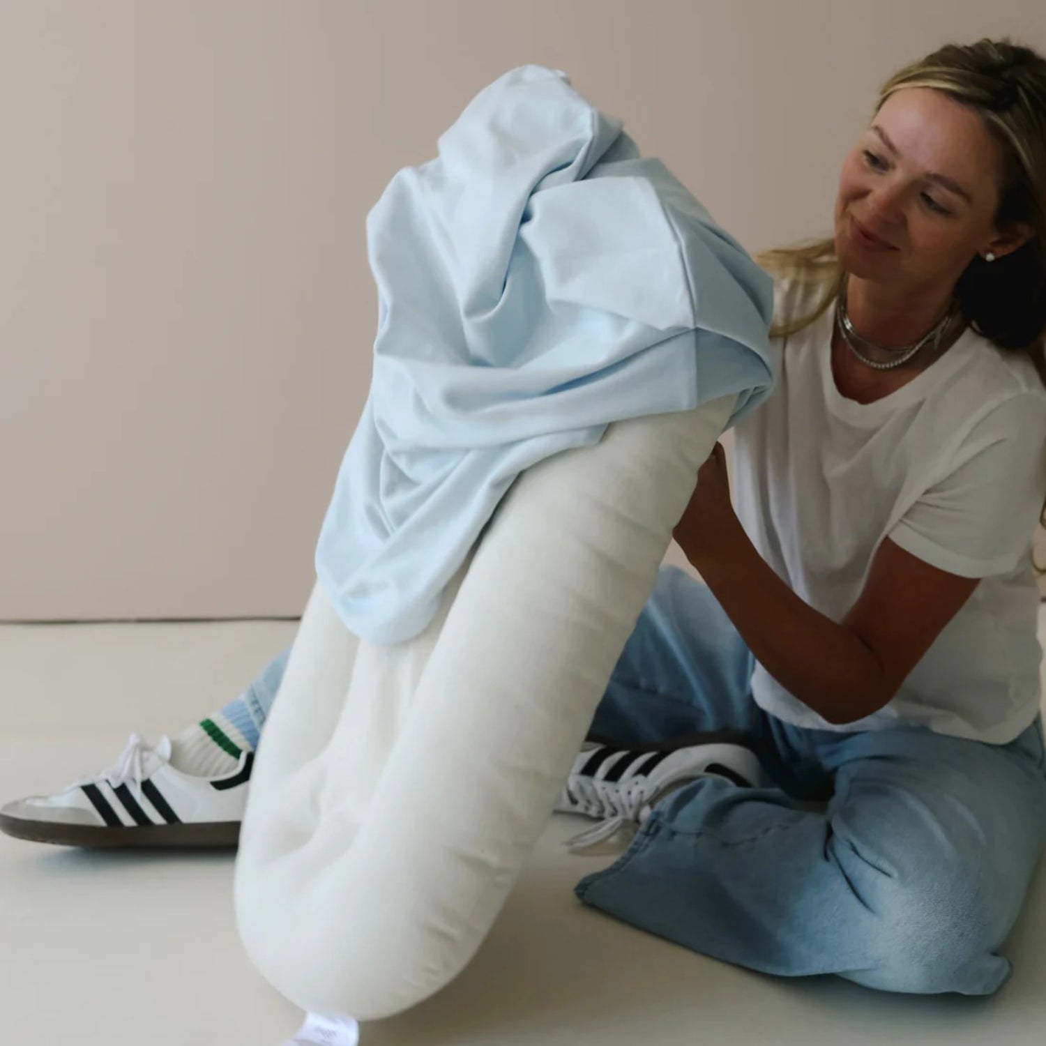 Parent placing Bluebell Snuggle Me lounger cover over cushion – lifestyle view showing soft, stretchable cotton in use