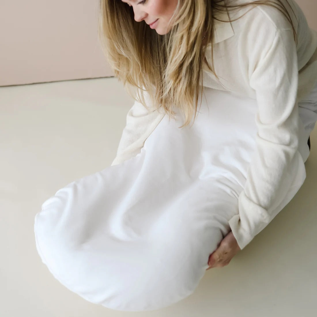 Parent applying Snuggle Me lounger cover in Natural β lifestyle view capturing gentle stretch and ergonomic lounger shaping