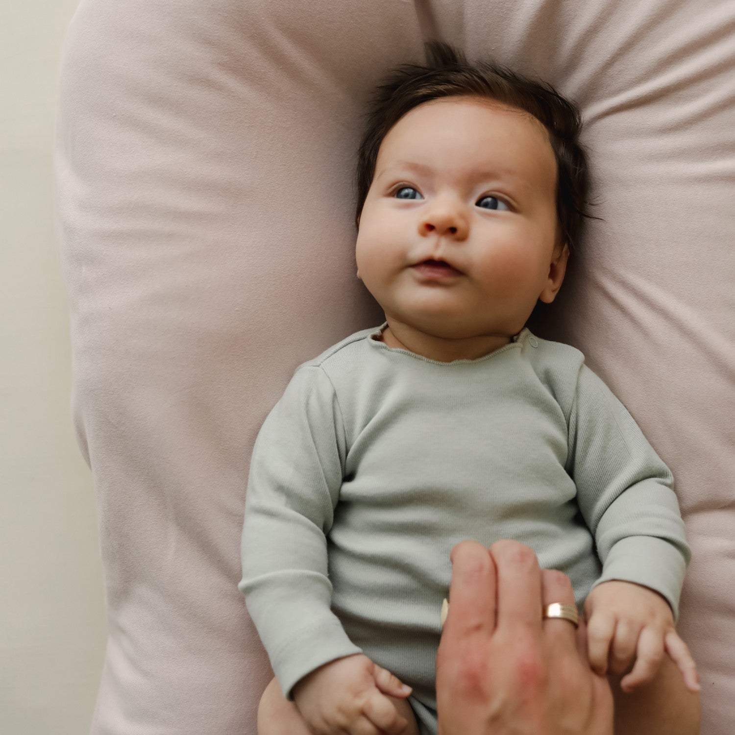 Close-up of a baby resting in the newborn lounger with the petal cover, highlighting the soft, organic cotton fabric