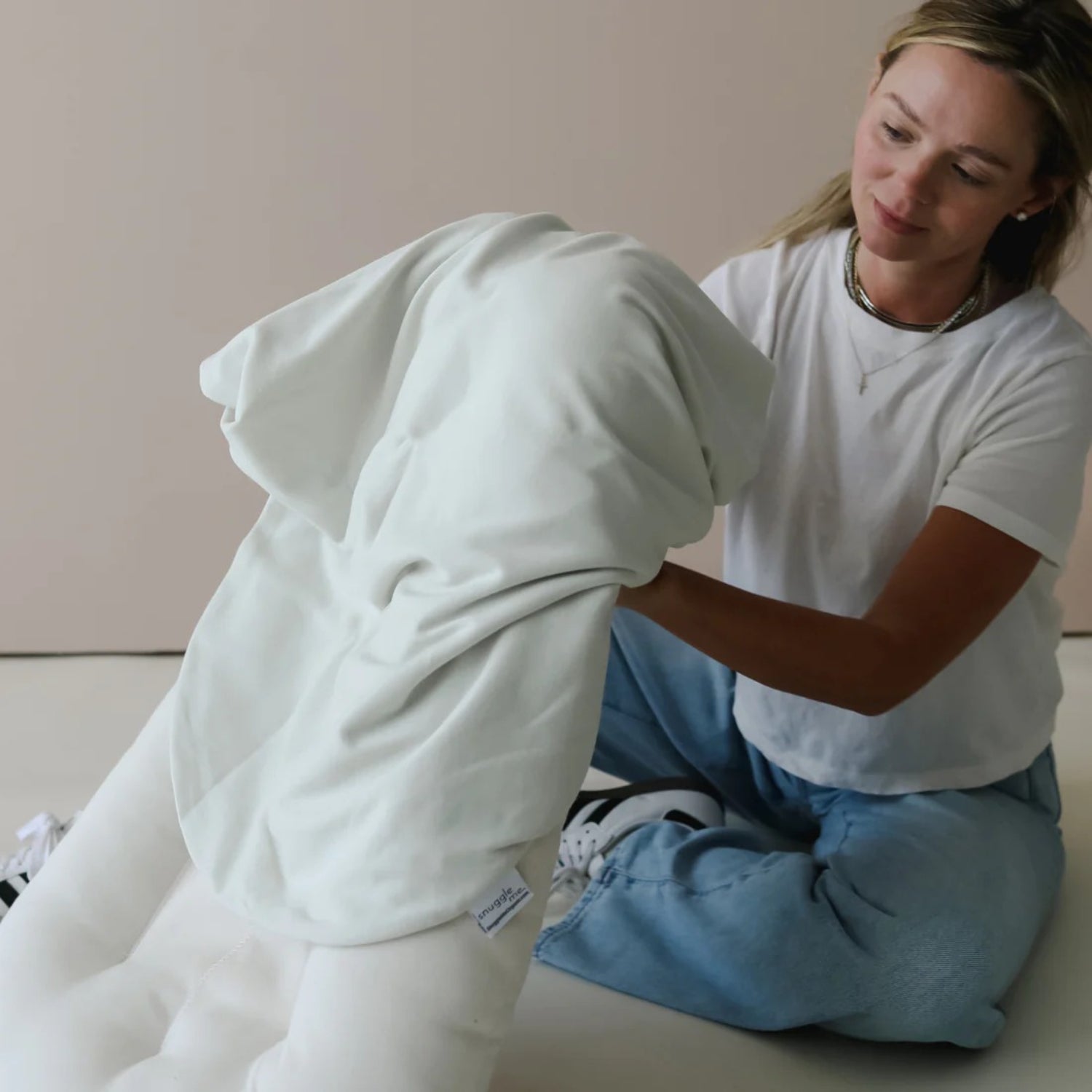 Snuggle me lounger cover sage shown mid-application β flexible fit helps parents adjust easily for daily use.