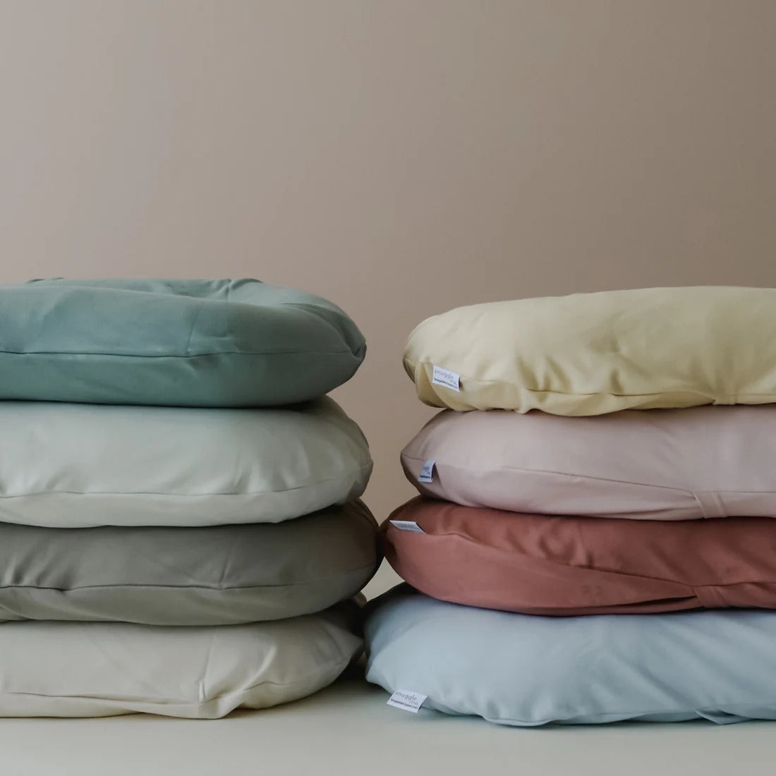 Stack of Snuggle Me lounger covers in assorted tones β lifestyle view showing soft, breathable fabric in soothing colour options