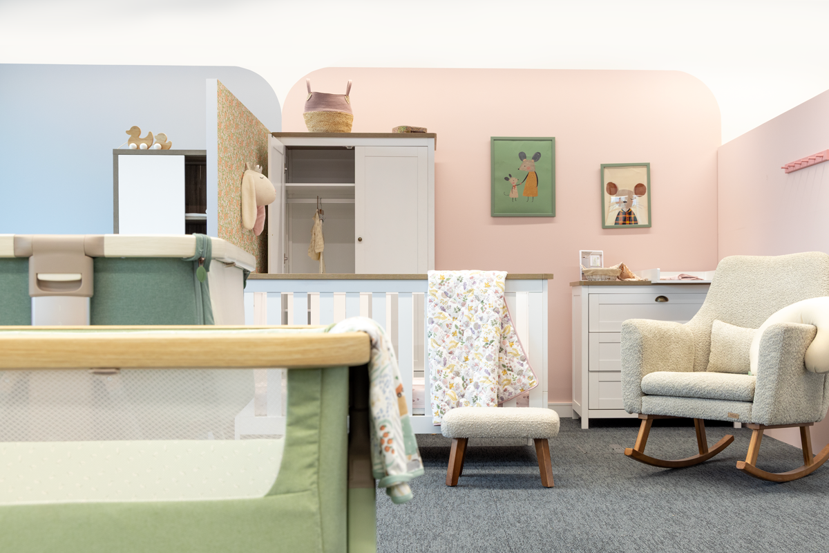 Showroom showcasing a baby nursery with furniture, including a crib, rocking chair, and storage unit.