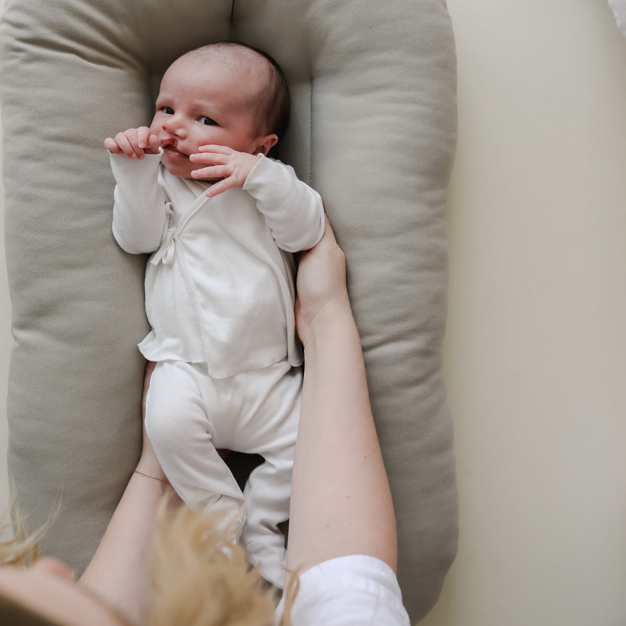 Newborn resting in the Snuggle Me Newborn Baby Lounger in Birch with arms supported, highlighting snug fit and gentle embrace