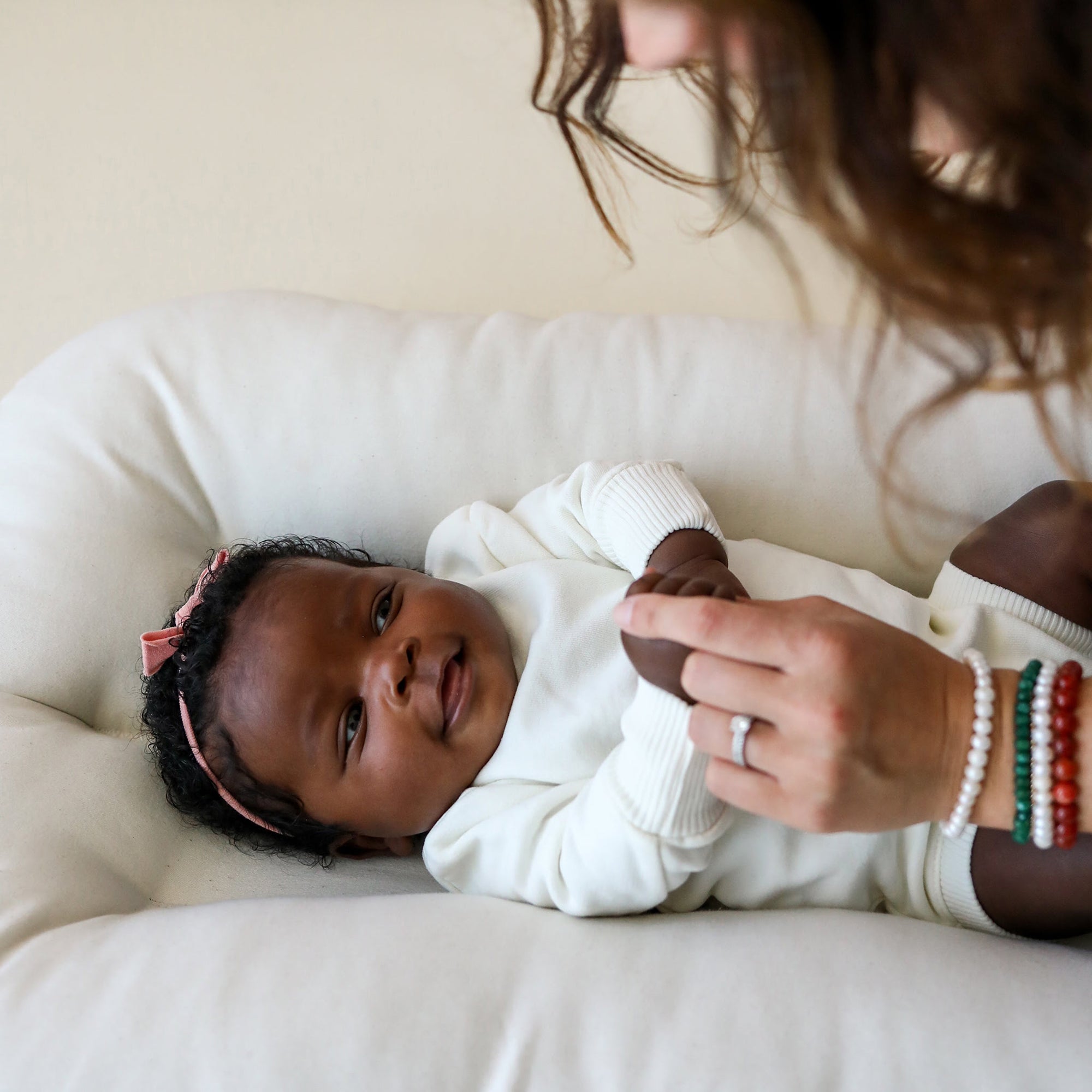 Close-up of baby lying in the Snuggle Me Newborn Baby Lounger in natural, designed to cradle baby gently with padded surround and neutral tone