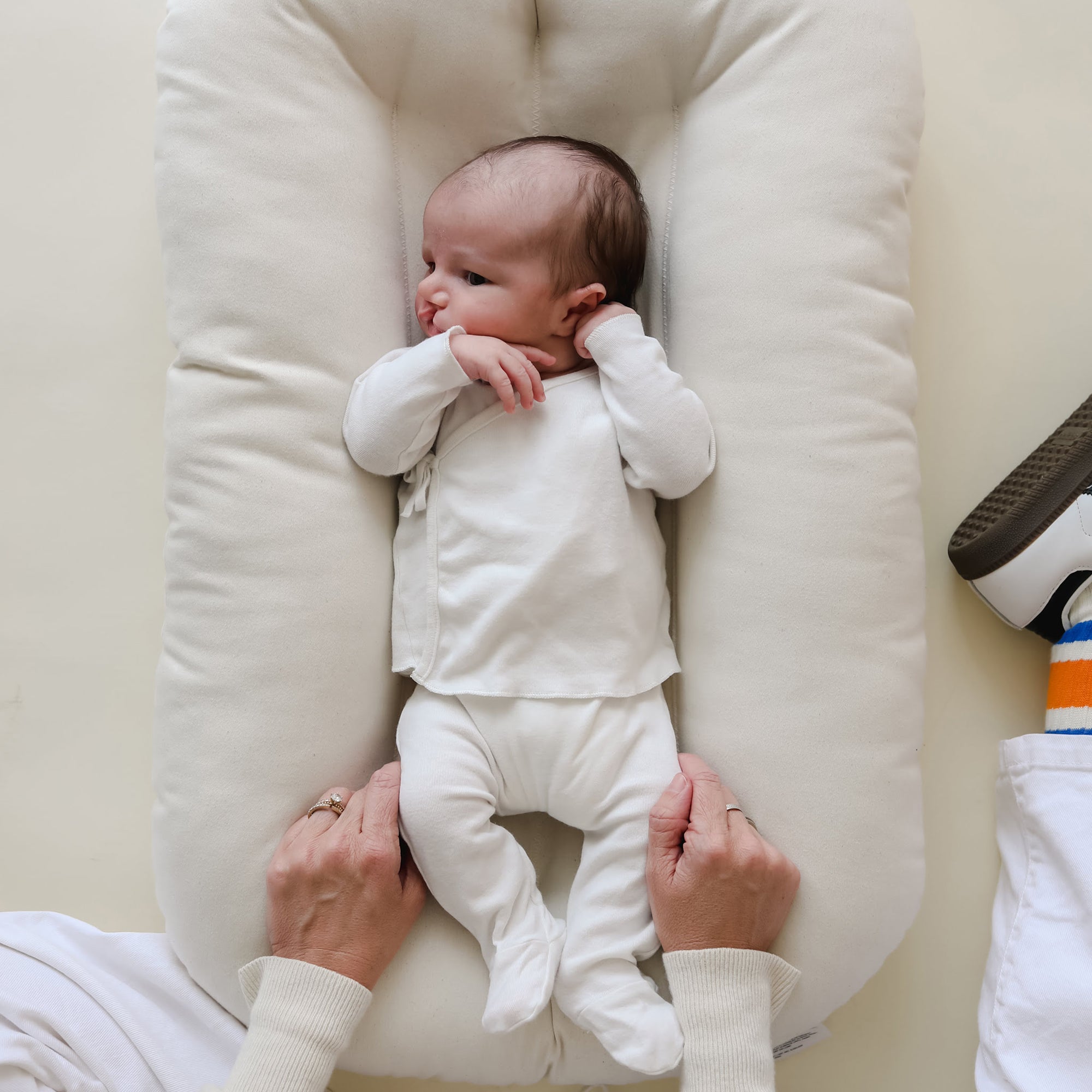 Overhead view of baby resting in the Snuggle Me Newborn Baby Lounger in natural, with soft cotton fabric and supportive, hugging shape
