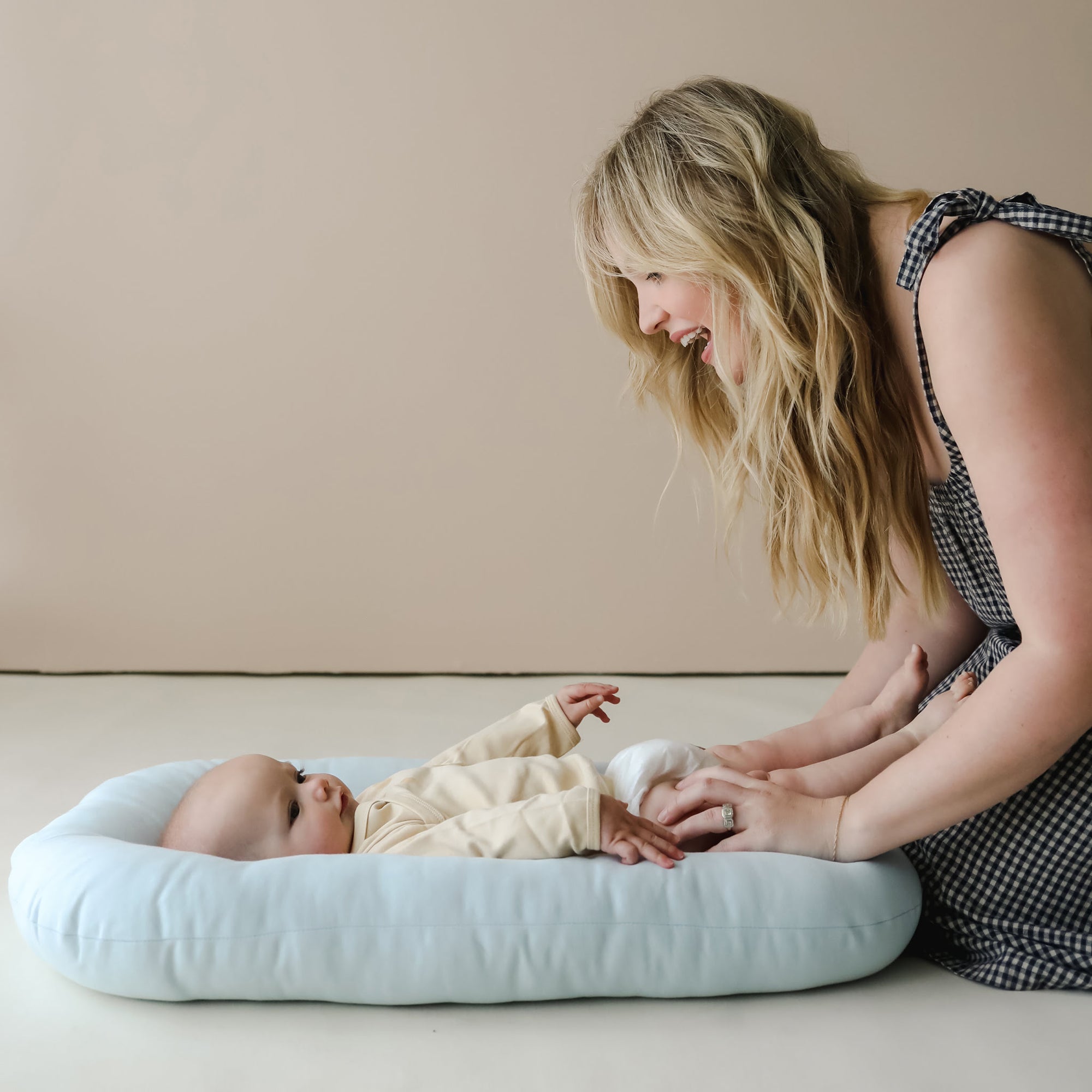 Baby lying on the Snuggle Me Newborn Baby Lounger in Bluebell, supported and calm, ideal for supervised lounging