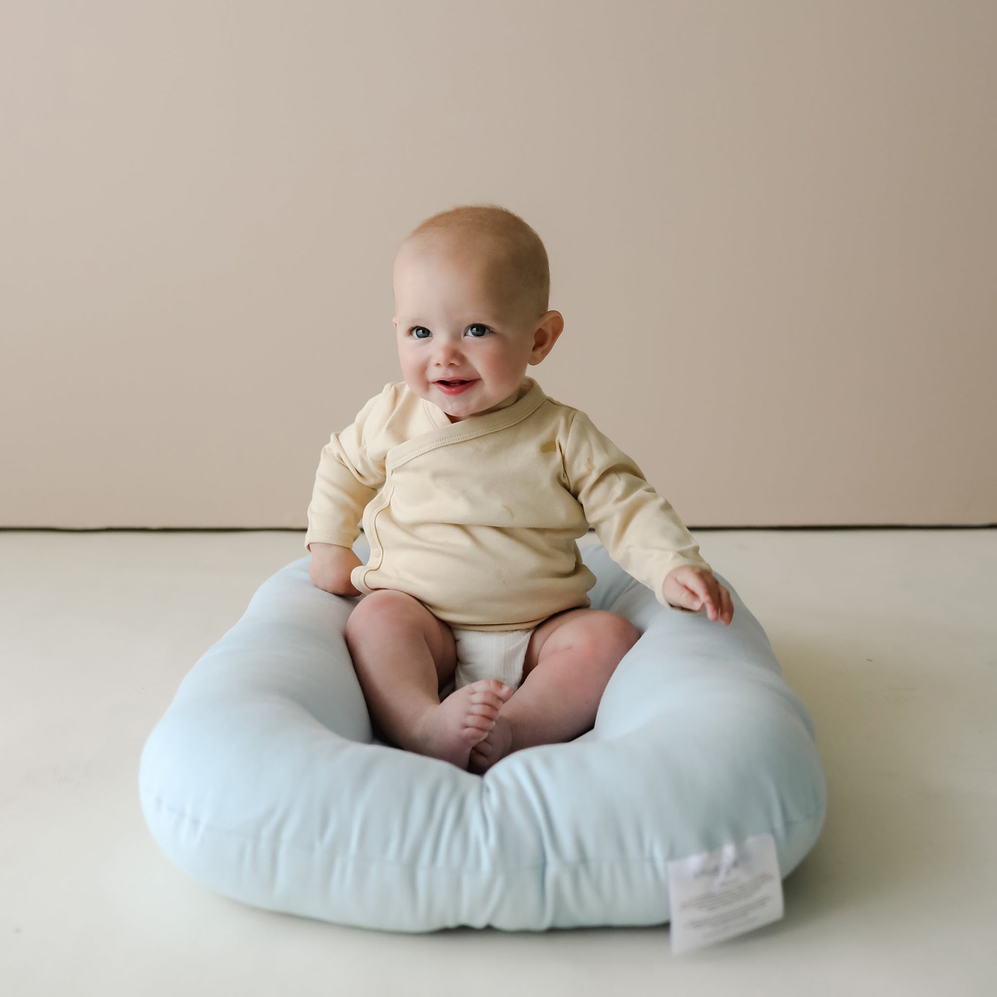 Baby sitting upright on the Snuggle Me Newborn Baby Lounger in Bluebell, showcasing versatility for tummy time and play