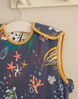 Baby sleep bag in Our Planet ocean print hanging on a peg rail, 6–18 months size, made from breathable bamboo cotton fabric.
