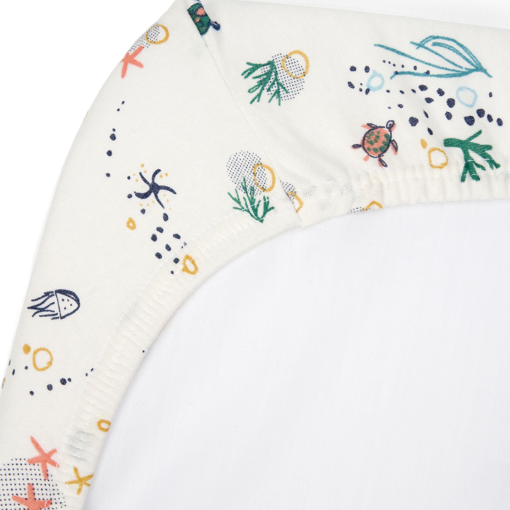 Close-up of Our Planet bedside crib fitted sheet in organic cotton, showing elasticated corner with playful sea life print detail
