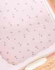 Overhead view of Tiny Tails bedside crib fitted sheet in a soft pink with strawberry print