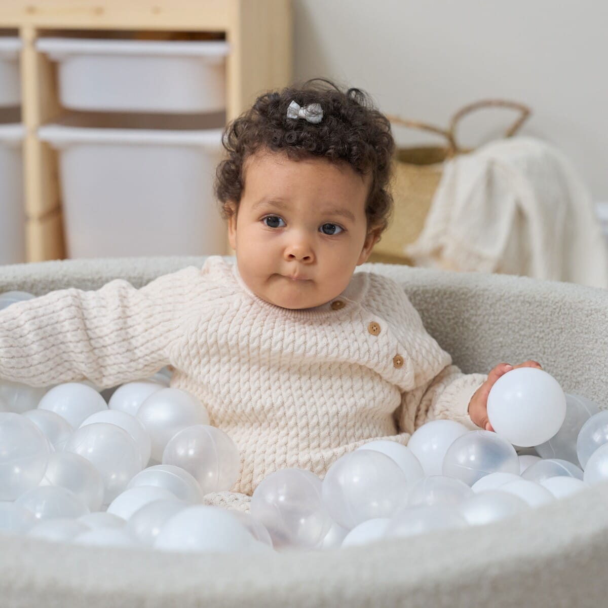 Bola Baby Ball Pit in Mushroom - lifestyle image of baby girl gripping on a ball pit ball