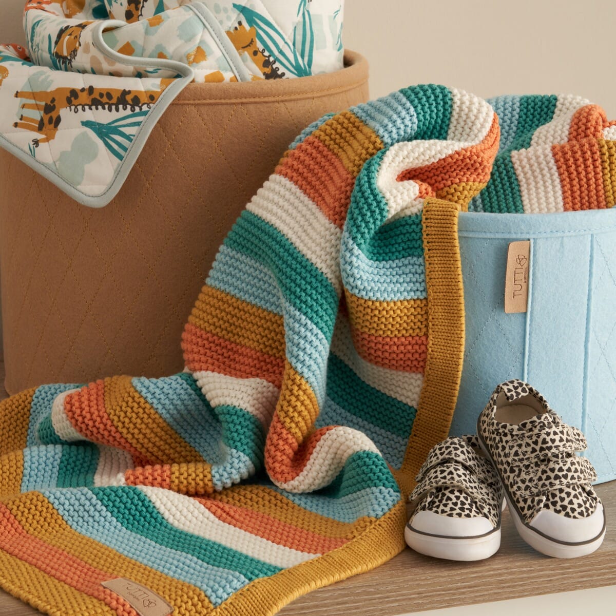 Lifestyle view of Run Wild chunky knitted baby blanket, draped in nursery with bold striped cotton knit adding warmth and style