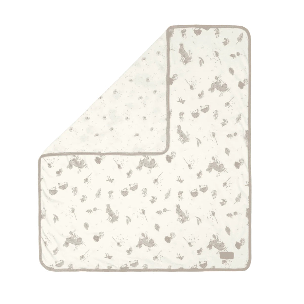 Folded corner cutout of the Cocoon coverlet, reversible quilted organic cotton with woodland animal prints for softness and cosy style