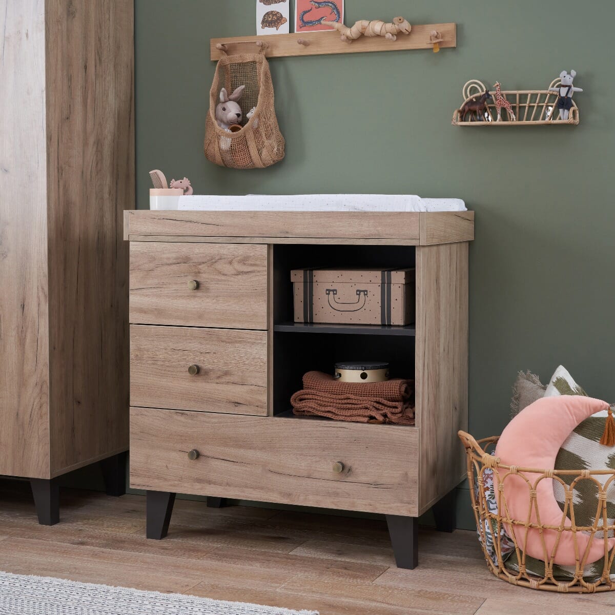 Styled nursery view of Como chest changer in distressed oak and slate grey, dressed with baby essentials and decor for a cosy, modern space