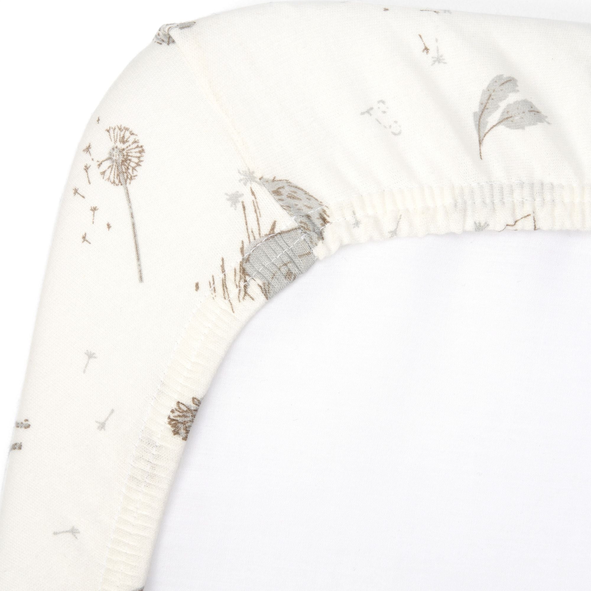 Close-up of Cocoon cot bed fitted sheet corner with elasticated edge, showing soft organic cotton fabric and delicate woodland print detail